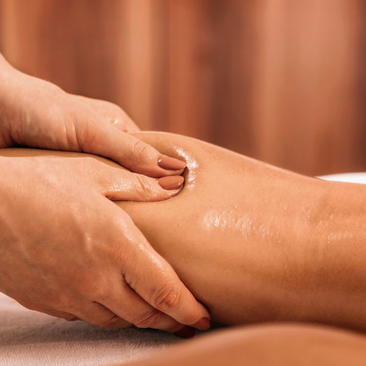 Manualità delicate e ritmiche di un massaggio linfodrenante sulle gambe