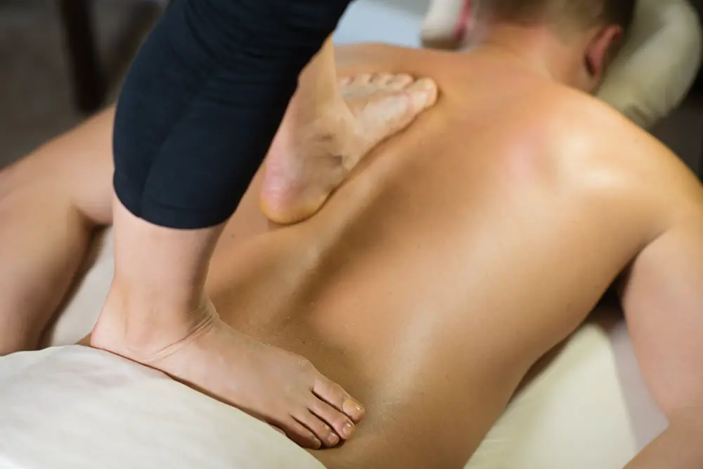 Massaggio con camminata sulla schiena: appoggio lento del piede lungo la muscolatura paravertebrale, nello studio di Roma Sud